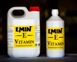 Två flaskor med E-vitamin för hästar. En stor dunk och en mindre flaska, båda med gul etikett och texten "EMIN - E - VITAMIN".