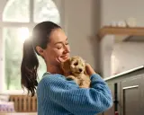 En kvinna håller en söt valp. Valpen ser ut som en liten, fluffig stjärna, en riktig boll av glädje.