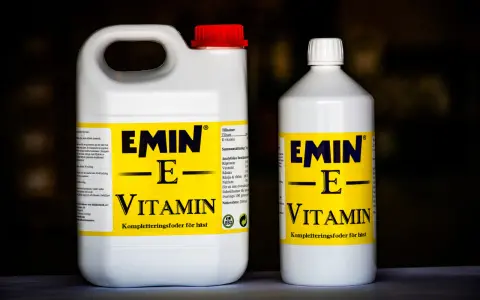 Två flaskor med E-vitamin för hästar. En stor dunk och en mindre flaska, båda med gul etikett och texten "EMIN - E - VITAMIN".
