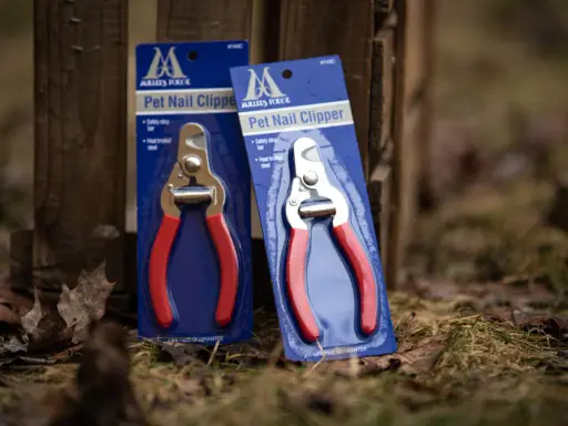 Två förpackningar med Millers klotång, med röda handtag och metallskär, står lutade mot ett trästaket.